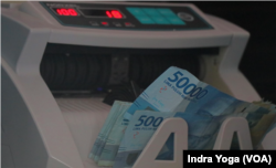 Mesin penghitung uang digunakan dalam transaksi penukaran uang pecahan uang kecil agar tidak terjadi kelebihan maupun kekurangan jumlah uang yang ditukar dan diterima oleh masyarakat. (Foto: VOA/Indra Yoga)
