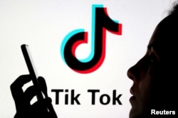 Seseorang memegang telepon pintar dengan latar belakang logo TikTok, 7 November 2019. (Foto: REUTERS/Dado Ruvic)