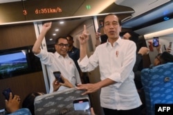 Presiden Joko Widodo (kanan) dan Menteri Perhubungan Budi Karya Sumadi (kiri) menunjuk ke arah layar yang menunjukkan kecepatan saat uji coba kereta cepat baru Bandung-Jakarta di Jakarta, 13 September 2023. (AKBAR NUGROHO GUMAY/Pool/AFP)